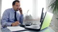 Angry businessman in the office talking on mobile phone