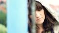 Sad beautiful woman by chain-link fence, outdoors, dolly shot HD