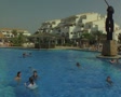 Pan from swimming pool to people by poolside Video