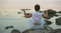 The girl sits on the seashore in a pose of meditation by a back Video