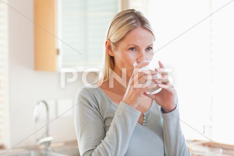 Woman In The Kitchen Drinking Water