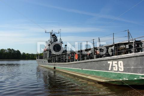 Stock photo of barcaza de transporte militar en la orilla del río contra un cielo azul