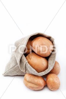 Stock photo of raw potatoes in burlap bag isolated on white background