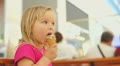 Adorable baby eat ice cream sitting on bench in mall