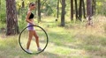 The young woman twists an hoop in park Video