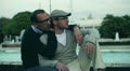 Two handsome men sitting on bench and smiling to the camera, slow motion