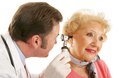 Doctor using otoscope to look inside a beatiful senior woman's ears