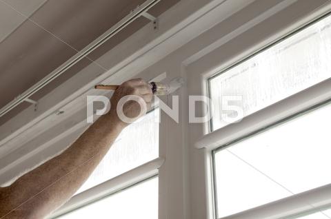 Stock photo of hand painting a wooden window