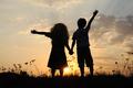 silhouette, group of happy children playing on meadow, sunset, summertime