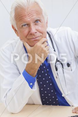 Senior Male Doctor With Stethoscope At Desk