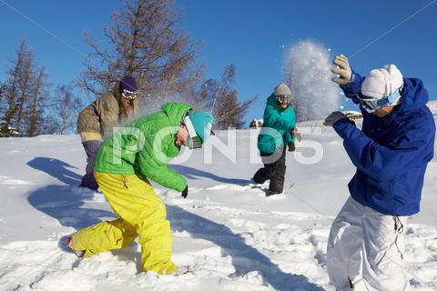Stock photo of four teenagers throwing snowballs outdoors