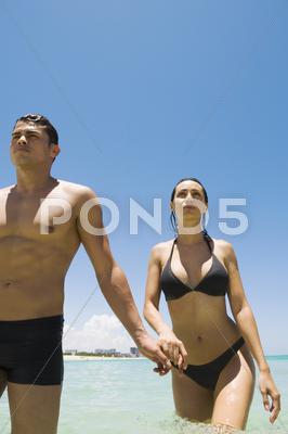 Stock photo of casal hispânico, segurando as mãos em água