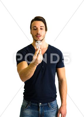Stock photo of handsome young man looking at lightbulb