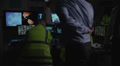 Security personnel watching the screens in a dark system control room
