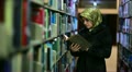 Female student wandering between shelves, searching for books