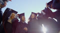 Happy multi-ethnic friends on graduation day throw their caps into the air