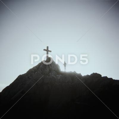 A Person Standing Below A Crucifix On A Mountain Top, Mount Saint Michel,