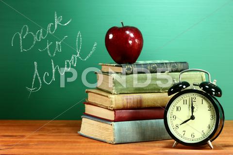 School Books, Apple And Clock On Desk At School