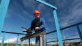 Elderly Caucasian worker in a helmet at the factory with the pipe valve Video