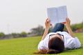 young woman reading a book in the park