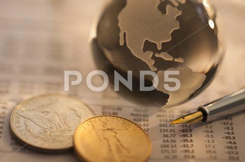 A Globe On Business Papers With Some Coins