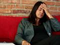 Businesswoman on sofa in home having headache NTSC