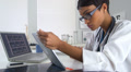 Doctor using laptop computer and pad at same time to review x-rays