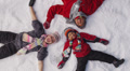 Family laying in winter snow, overhead shot