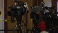 Reporters and cameras waiting for a press conference to begin.
