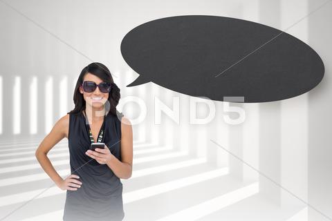 Composite Image Of Happy Brunette Holding Smartphone With Speech Bubble