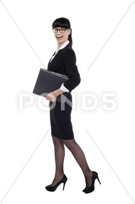 Stock photo of Cheerful smart business lady walking with files