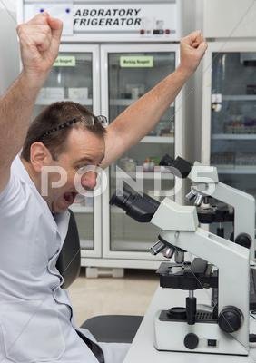 Happy Cheerful Man Celebrating Success While Working With A Microscope In A Lab