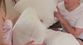 Attractive couple play pillow fight in bed and start kissing Video