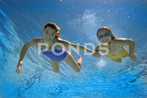 Mother And Daughter (8-10) In Swimming Pool, Smiling, Portrait, Underwater Vi
