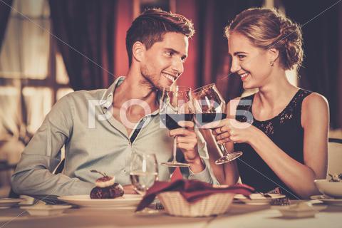 Beautiful Young Couple With Glasses Of Red Wine In Luxury Restaurant