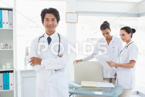 Doctor Smiling In Front Of Work Colleagues