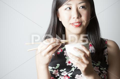 Portrait Of Asian Woman Eating With Chopsticks
