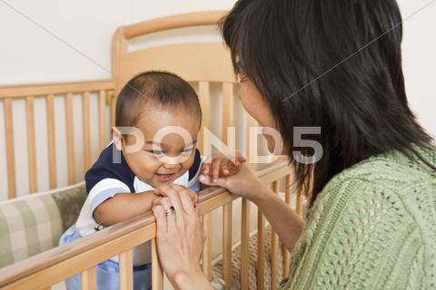 Baby Inside Crib, Holding Hands With Mother