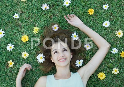Woman Lying On Grass With Flowers Scattered Around Head
