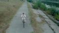 Young positive man riding bicycle fast on park alley, aerial Video