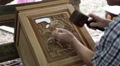 Man cuts a picture with elephants out of wood at a teak factory in Thailand Video