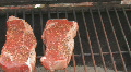 Steaks cooking on charcoal grill Clip 1 Footage