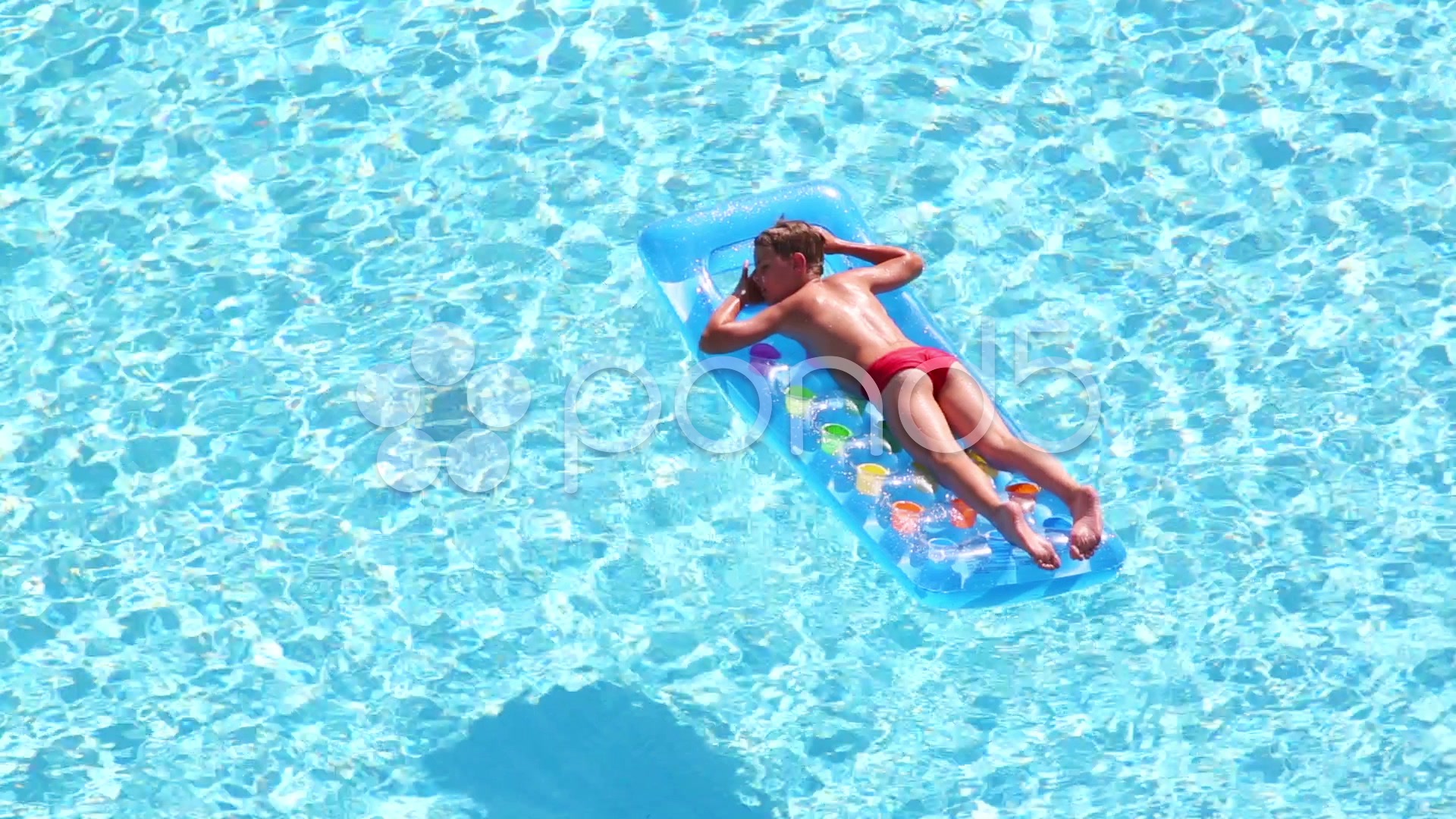 Video Boy floats in pool lying on stomach at inflatable mattress 34415099