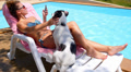Tanned Woman Using Smart Phone by the Poolside with a Dog. Caucasian Female Video