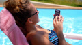 Woman Surfing Internet in the Phone while Relaxing in Pool near Hotel. Video