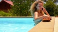 Young Beautiful Woman Talking on Cell Phone and Eating Pineapple in Pool. Video